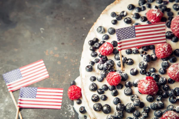 Patriotic American flag cake with blueberries and strawberries on vintage white background