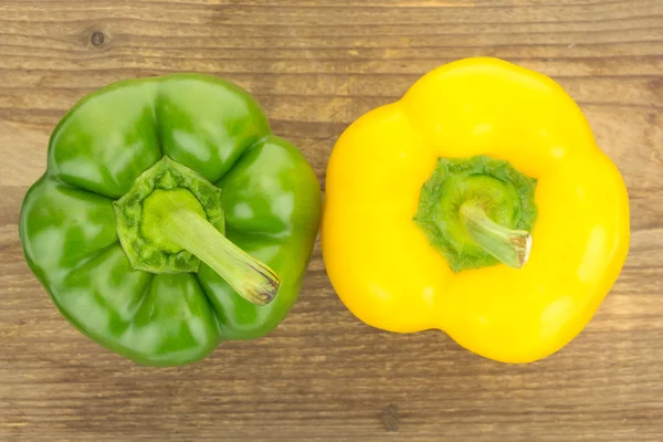 Fresh yellow and green bell peppers, on wooden surface.