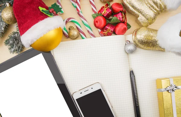 Tablet, smartphone and open notebook with winter festive ornaments.