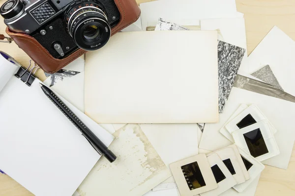 Old camera, notebook and pen on stack of photos and transparency slides