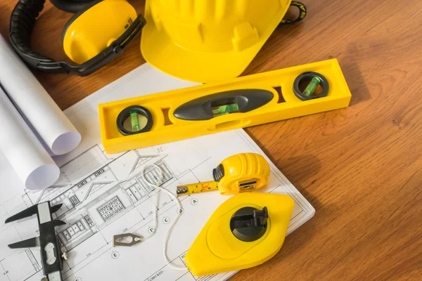 Construction plans with yellow helmet and drawing tools on bluep