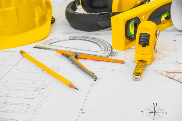 Construction plans with yellow helmet and drawing tools on bluep