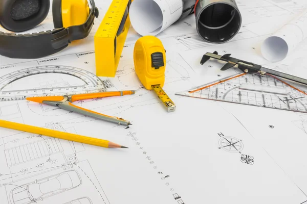 Construction plans with yellow helmet and drawing tools on bluep