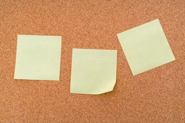 Post it notes on cork board .
