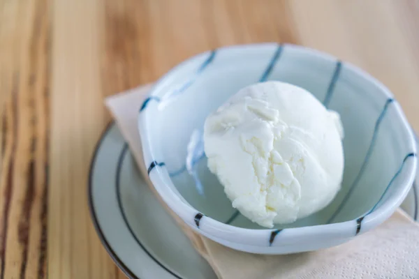 Milk ice cream in bowl on wood table .