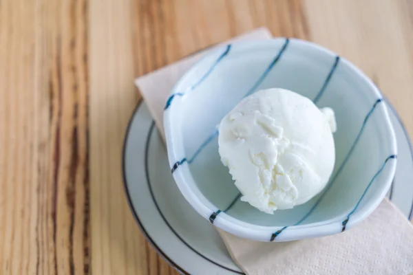 Milk ice cream in bowl on wood table .