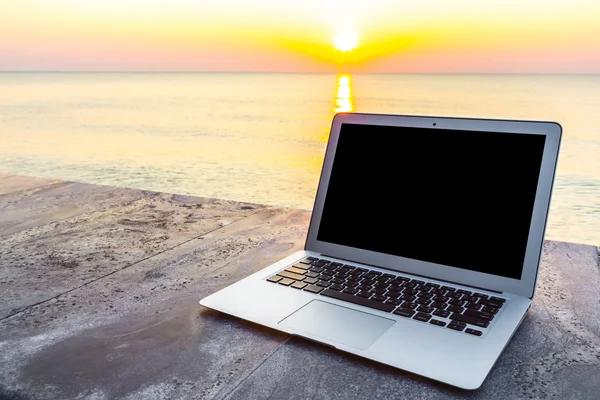 Laptop on table at sea sunset in summer time