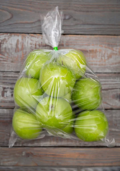 Apple fruit in plastic bag on wood table