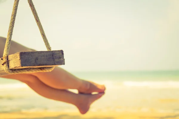Woman leg  on a swing at tropical sea beach