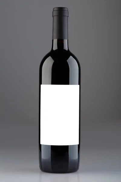 Red wine bottle with blank label on gray background, clipping path