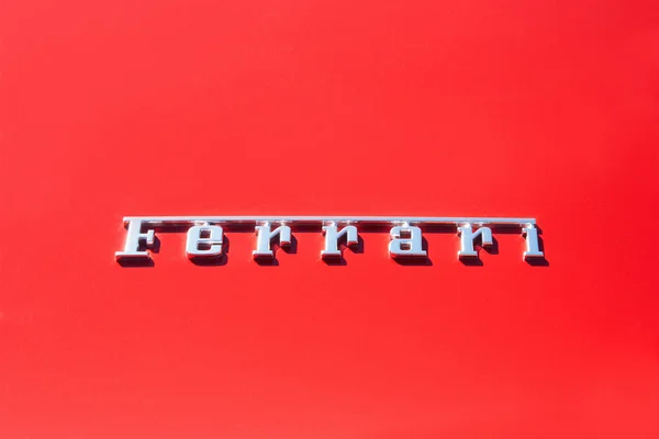 Silver Ferrari logo on red metal luxury car