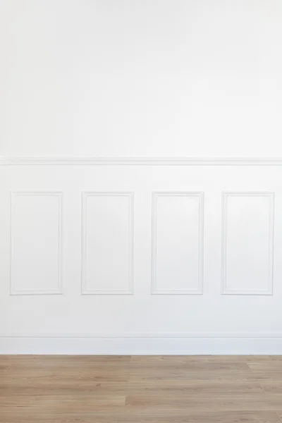 Empty white room with wooden floor and wood trimmed wall