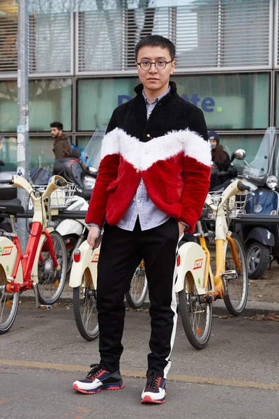 Man with black, red, white, jacket poses for photographers before Emporio Armani fashion show