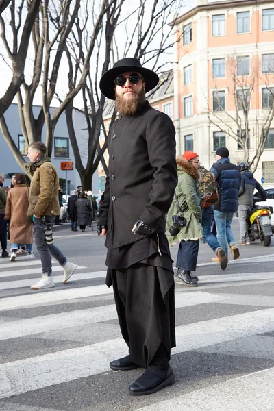 Man in black coat poses for photographers before Emporio Armani fashion show