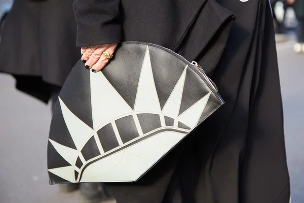 Woman poses for photographers with Statue of Liberty bag, street style