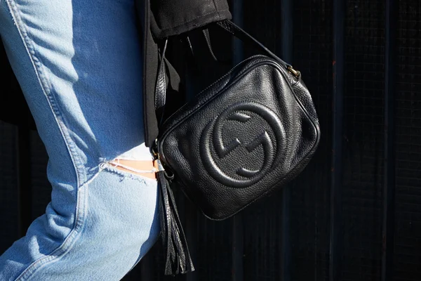Woman poses for photographers with Gucci black leather bag