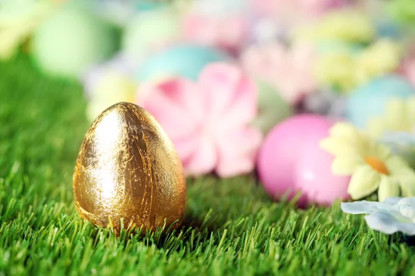 Colorful Easter eggs on grass with golden egg
