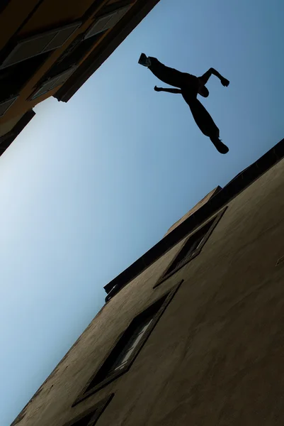 Man jumping over building roof vertical image