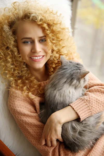 Woman and cat beside window in the room