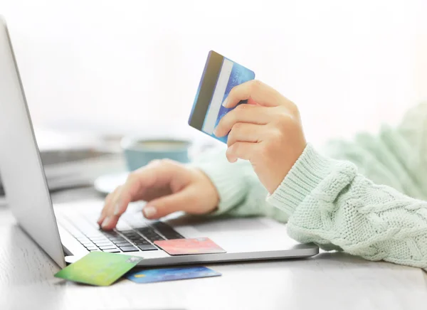 E-commerce concept. Woman with credit card, laptop and cup of coffee, close up