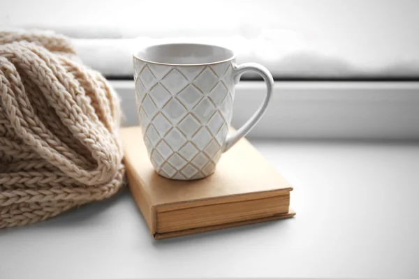 Cup of tea, book and knitted scarf