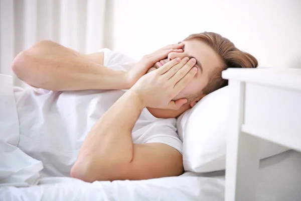 Young man in bed waking up