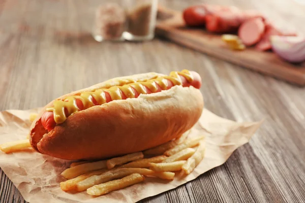 Hot dog with fried potatoes on craft paper