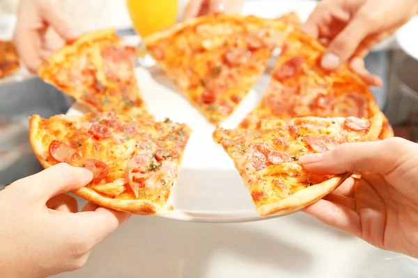 Friends hands holding hot pizza, close up