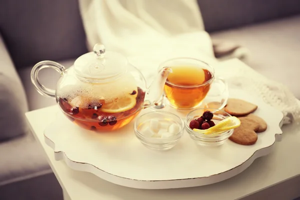 Tea set with hot tea and breakfast on a white wooden mat on the table
