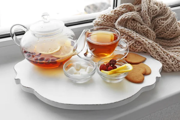 Tea set on a white wooden mat on the windowsill