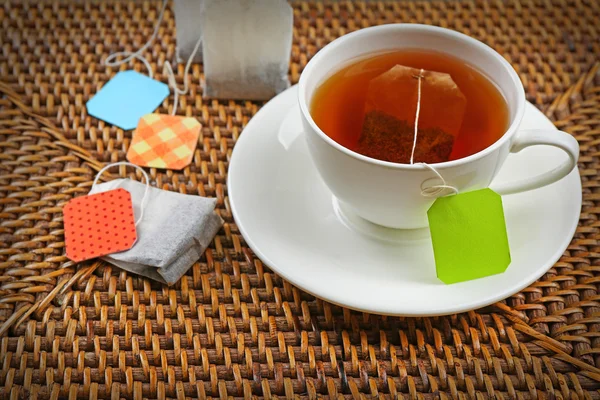 Cup of tea with tea bags on brown background