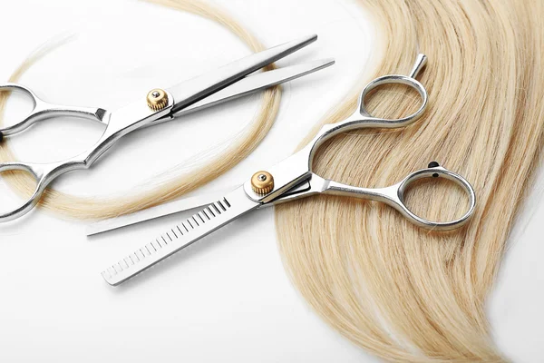 Hairdresser\'s scissors with strand of blonde hair, isolated on white