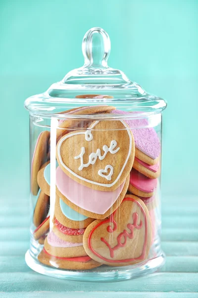 Assortment of love cookies in jar on blue background