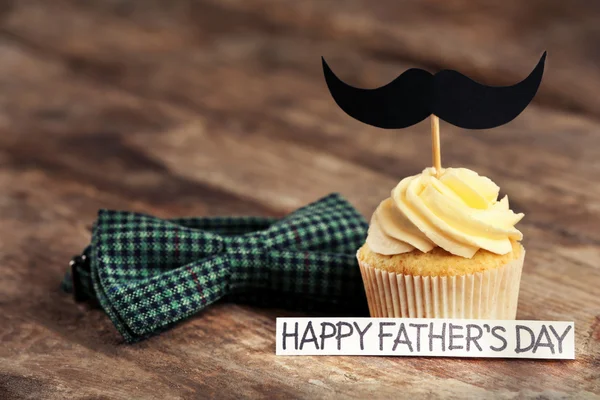 Happy fathers day special cupcake and bow tie on wooden table