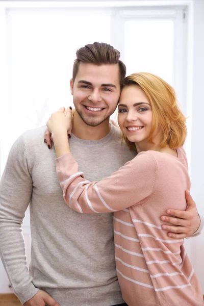 Young couple in love embracing beside the window