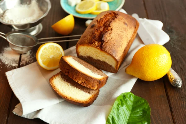 Delicious sweet cake bread with lemons on wooden table closeup