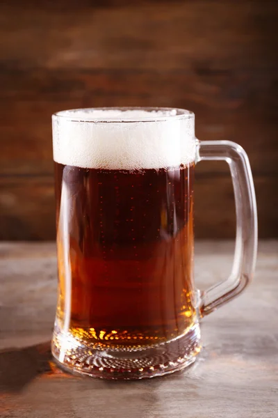 Glass mug of light beer on wooden table, close up