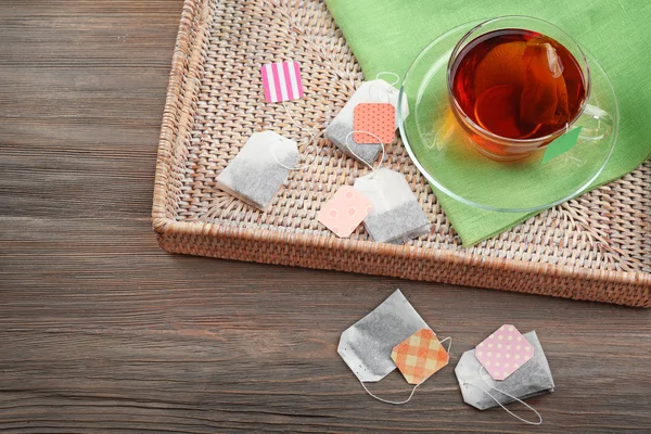 Cup of tea with tea bags in box on wooden table background