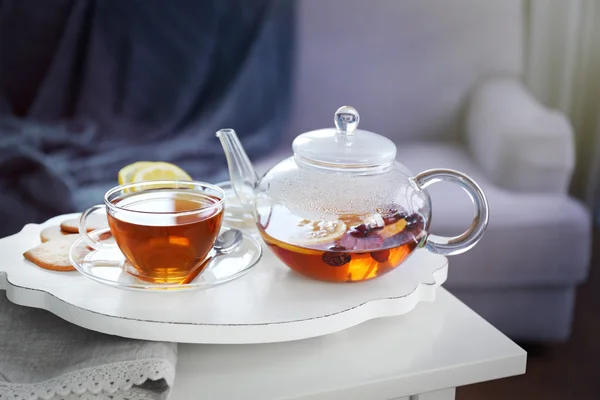 Tea set with hot tea and breakfast on a white wooden mat on the table