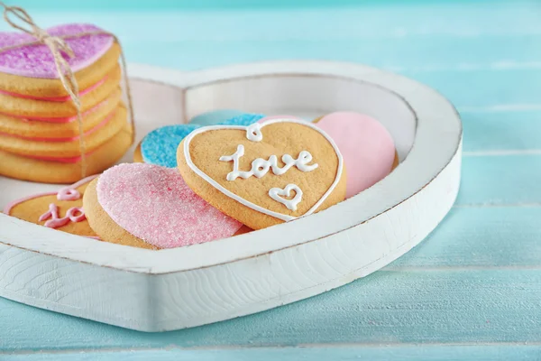 Assortment of love cookies in box on blue background, closeup