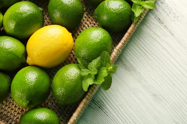 Wicker basket of limes and one lemon on table
