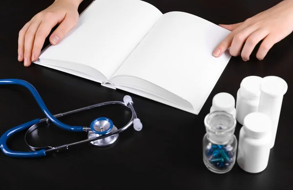 Medical book with pills and blue stethoscope