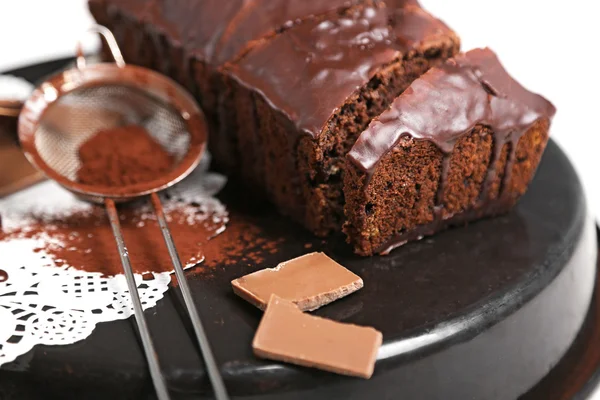 Chocolate sliced cake with icing and cocoa powder on baking dish