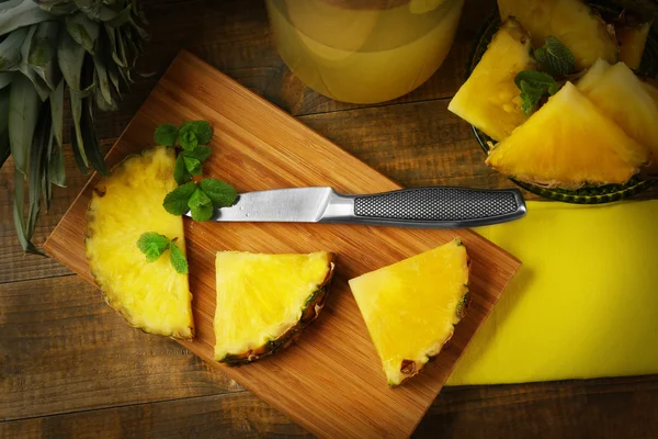 Juicy pineapple slices with fresh mint on wooden cutting board