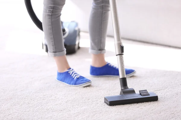 Cleaning concept. Young woman cleaning carpet with vacuum cleaner, close up