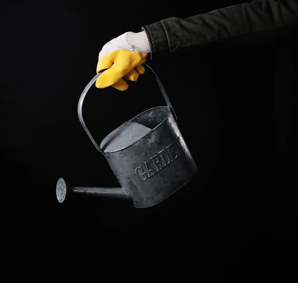 Hand holding metal watering can
