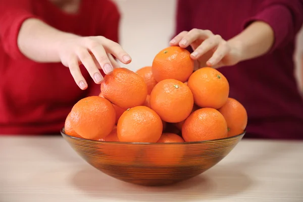 Woman taking tangerines from the bowl