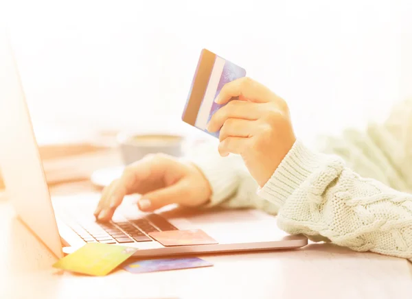 E-commerce concept. Woman with credit card, laptop and cup of coffee, close up