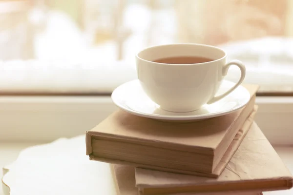 Cup of tea, book  and warm knitted plaid on windowsill, close up