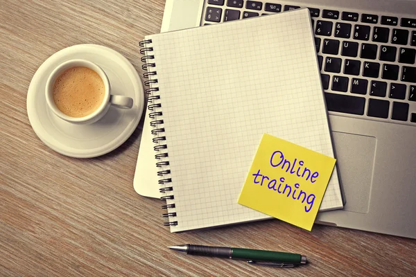 Online training written on sticky note, laptop, notebook and cup